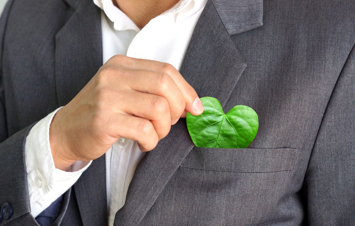 Businessman holding a green heart leaf / Business with corporate