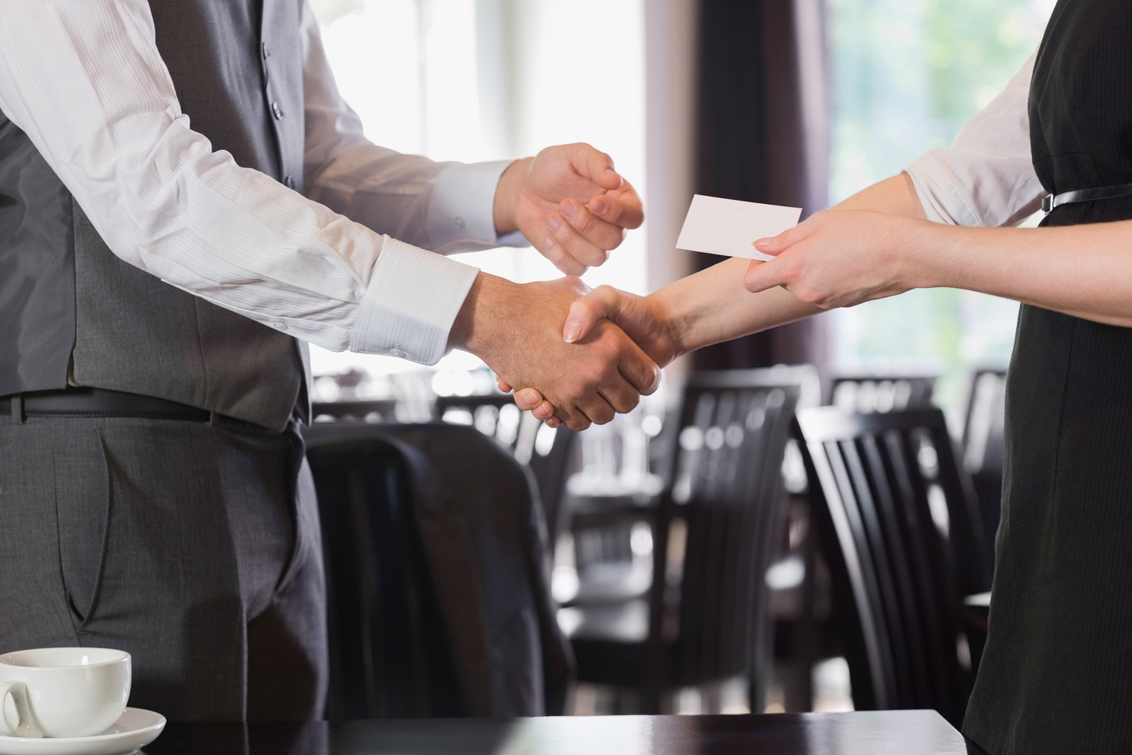 Busines people shaking hands after meeting and changing cards in restaurant